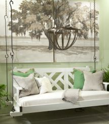 a white swing bed sitting in front of a green wall with potted plants on it