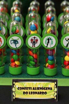 there are many small candy jars with different candies in them on the display table