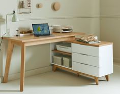 a laptop computer sitting on top of a wooden desk next to a white drawer and shelf