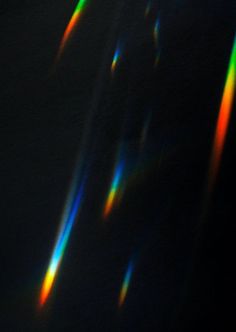 the sun is shining brightly through some thin rainbow colored lines in the dark sky,