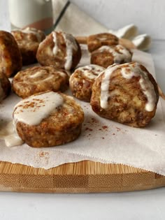 a wooden cutting board topped with donuts covered in icing and cinnamon on top of a table