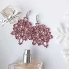 a pair of pink earrings sitting next to a bottle of perfume on top of a table