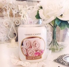 a white candle sitting on top of a table next to a vase filled with flowers