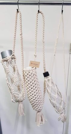 three macrame hangings with tags attached to the handles and sides, one is white