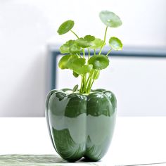 a green vase with some plants in it