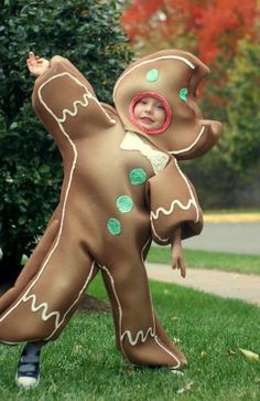 a young child in a costume standing on the grass with his arms out and legs spread wide