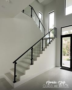 a white staircase with black handrails and glass doors