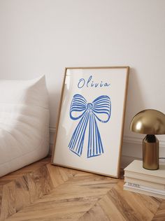 a white bed with a blue bow on the headboard next to a framed poster