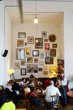 a group of people sitting at tables in a room with pictures on the wall behind them