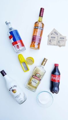 various alcohol bottles are arranged on a white surface, including lemons and vodka bottle