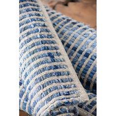 a blue and white striped pillow on top of a wooden table next to a wall