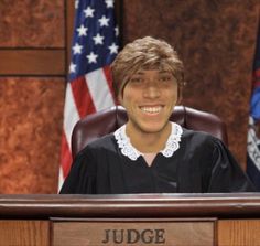 a judge sitting at a desk with flags in the background and an american flag behind her