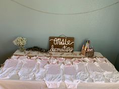 a table that has some clothes on it and a wooden sign above it with writing