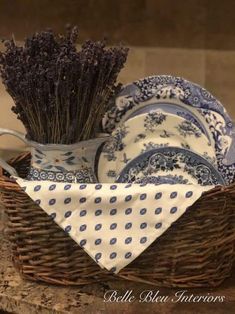 a basket filled with plates and lavenders on top of a table