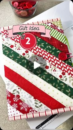 a pile of christmas paper sitting on top of a table next to a bowl of candy