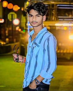 a young man standing in front of a bus at night with his hand holding scissors