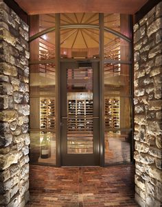 an entrance to a wine cellar with stone walls and glass doors that lead into it