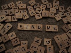 scrabble tiles spelling the word find me on a carpeted floor with letters arranged around it