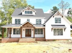 a large white house sitting on top of a dirt field