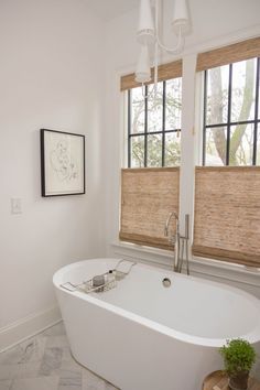 a white bath tub sitting next to two windows