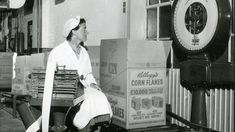 a black and white photo of a woman sitting on a bench next to stacks of boxes