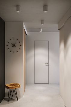 an empty room with a clock on the wall and a bench in front of it