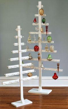 a white christmas tree with ornaments hanging from it's sides on a wooden floor