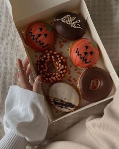 a box filled with lots of different types of doughnuts on top of a bed