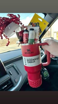 a person holding a cup filled with items in their hand while sitting in a car