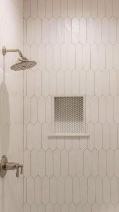 a bathroom with white tile and hexagonal pattern on the wall, shower head