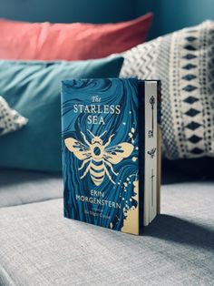 a book sitting on top of a bed next to pillows and pillows in the background