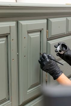 a person in black gloves painting a cabinet