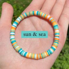 a hand holding a bracelet that says sun and sea