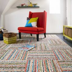 a living room with a red chair and colorful rug