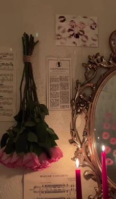 a mirror and some flowers on a wall with candles in front of it that are lit