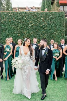 the bride and groom are holding hands in front of their wedding party