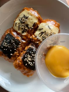 a white plate topped with food next to a bowl of mustard and ketchup