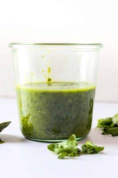 a small glass bowl filled with green sauce and garnished with parsley leaves