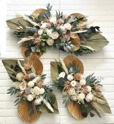 three decorative wall hangings with flowers and leaves on the side of a brick wall