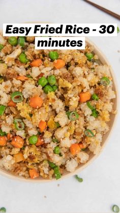 a bowl filled with rice and vegetables on top of a white countertop next to green onions