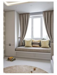 a window seat in front of a large window with curtains on the windowsills