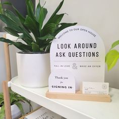 there is a potted plant next to a sign and some cards on a shelf