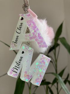 a pink and white initial ornament hanging from a plant