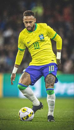 a soccer player in yellow and blue is on the field with a ball near his feet