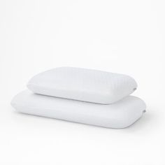 two pillows sitting on top of each other in front of a white background and one is folded up