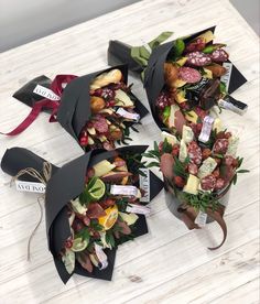 three black paper bags filled with assorted fruits and veggies on top of a wooden table