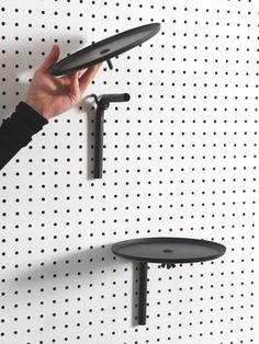 a person holding a tablet in front of a wall mounted shelf with two circular shelves