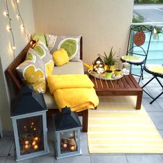 an outdoor patio with yellow and green decorations on the table, two small lanterns in front of