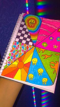 a hand holding a spiral notebook with colorful designs on it