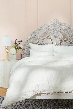 the bed is made with white linens and has an intricate headboard on it